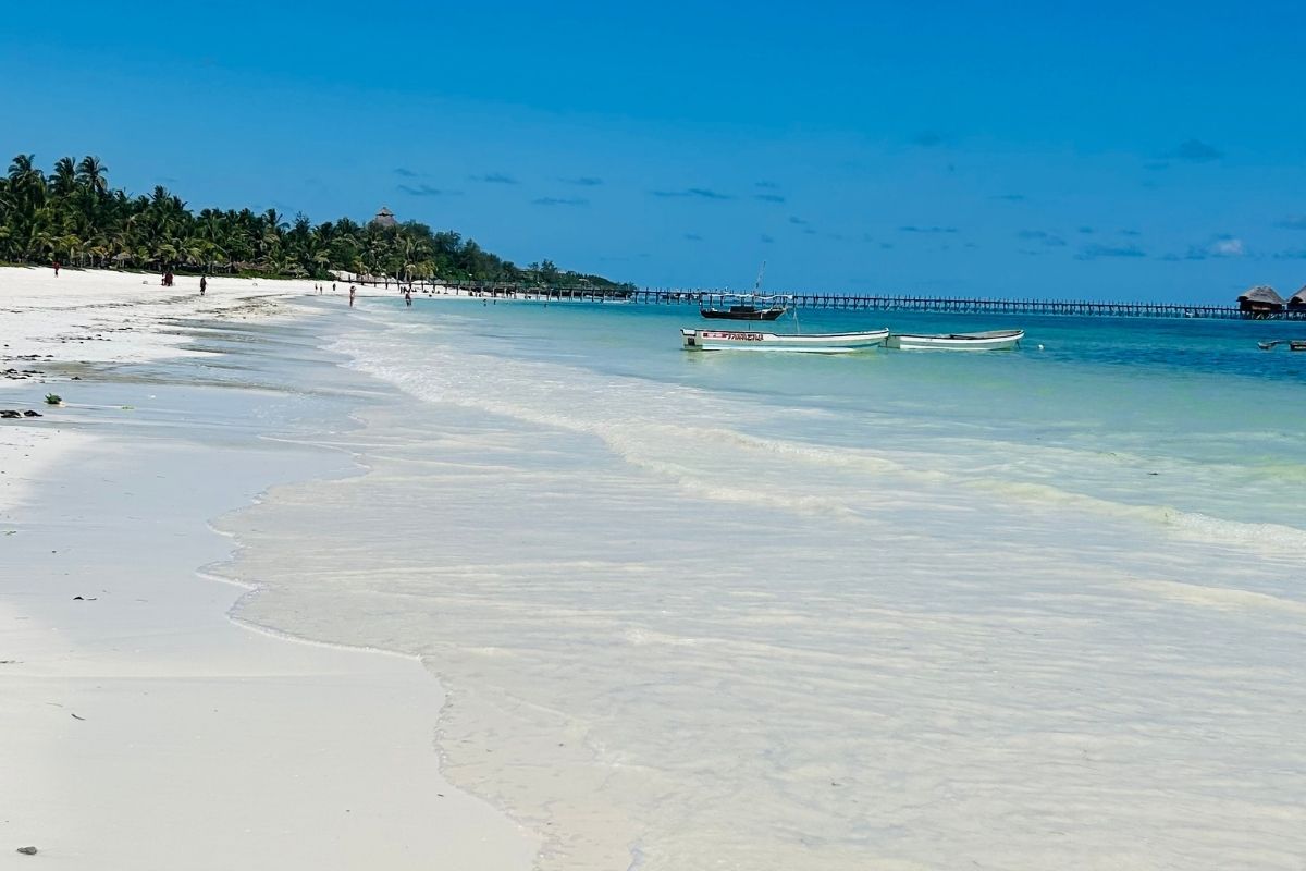 White sand beach with turquoise water and traditional wooden boats in Zanzibar