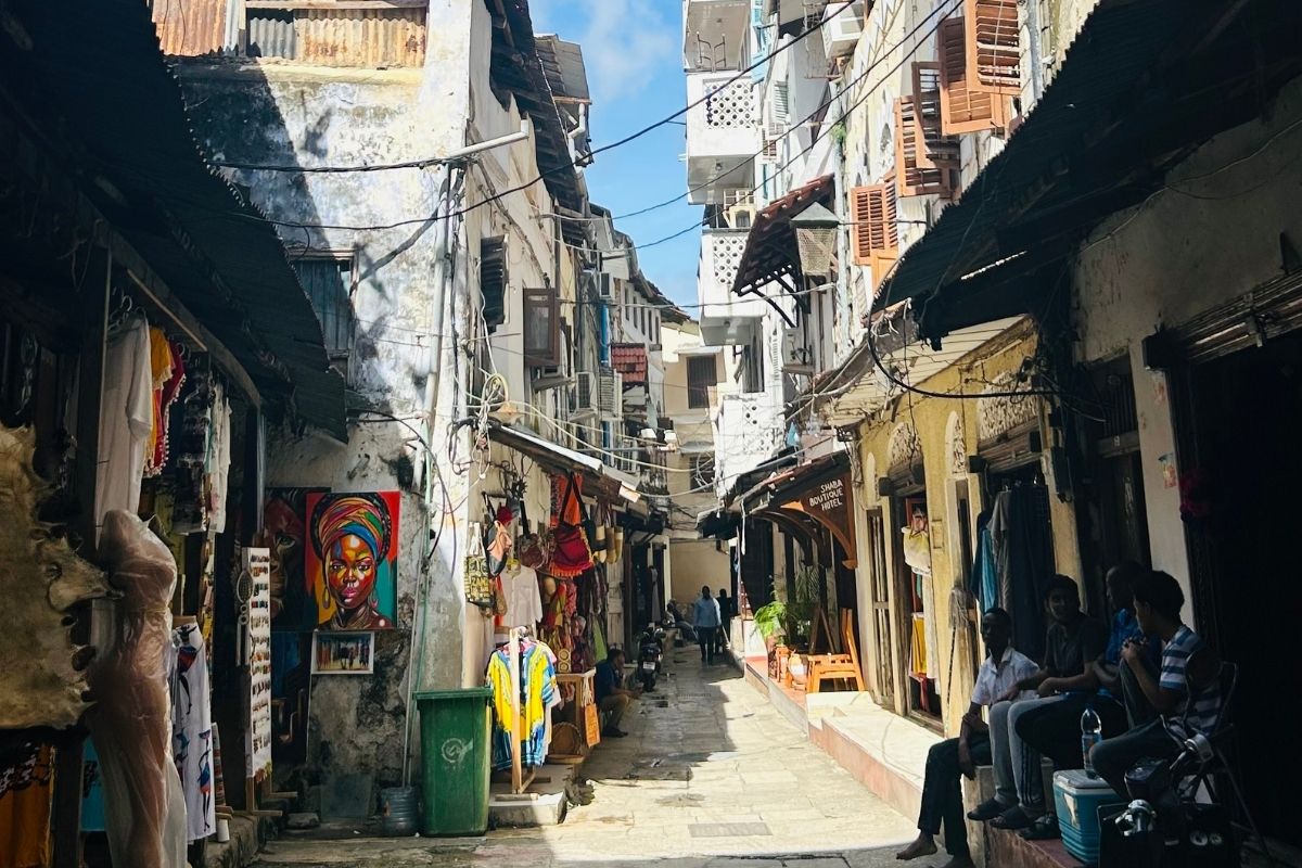 Narrow alley in Zanzibar Stone Town with colourful market stalls and historic carved buildings