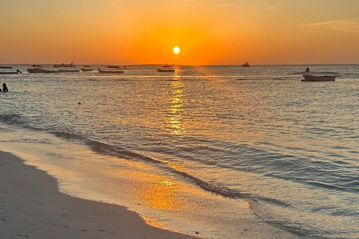 Dramatic golden sunset over the Indian Ocean with traditional fishing boats silhouetted